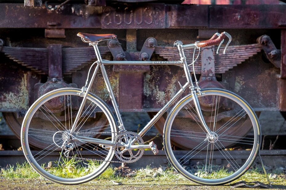 Marschall-Rennrad aus poliertem Edelstahl vor einem alten Eisenbahnwaggon