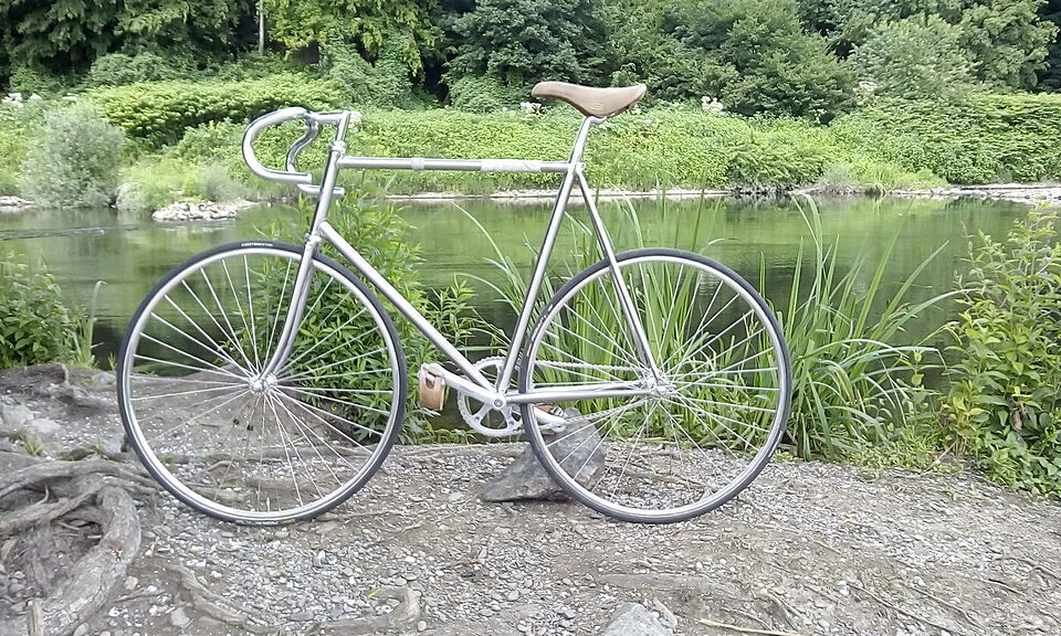 Singlespeed-Rahmen aus blankem Edelstahl mit Bullhorn-Lenker am Flussufer