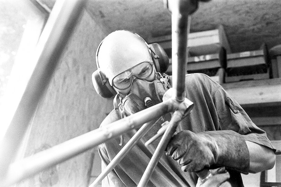 Uwe Marschall mit Schutzbrille und Atemmaske bei der Arbeit am Rahmen, Schwarzweißaufnahme